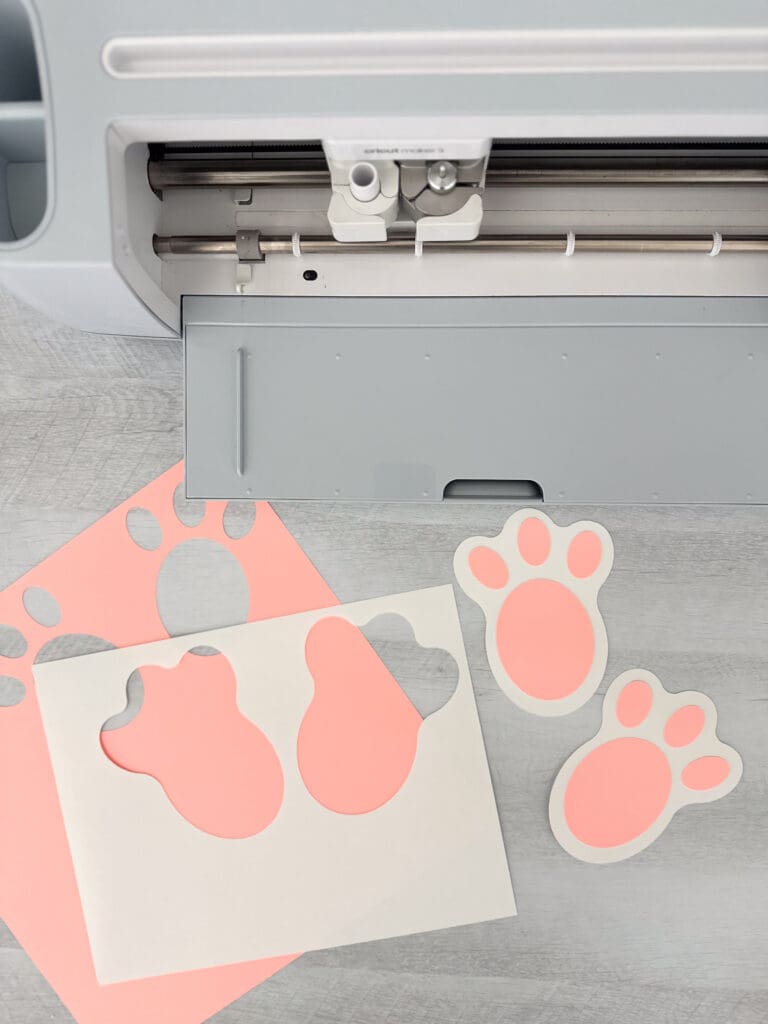 Cricut machine and bunny tracks cut from pink and white construction paper